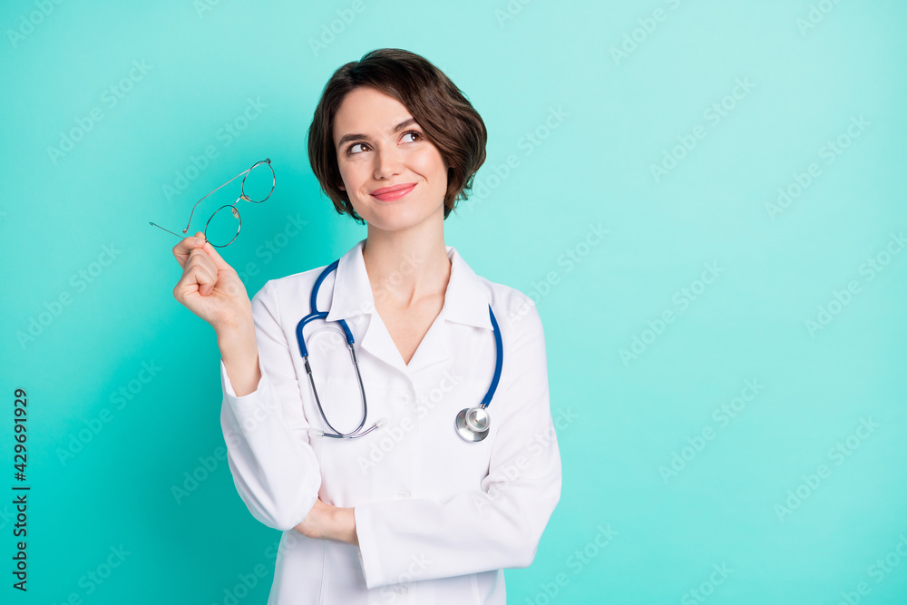 Wall mural Photo portrait of cheerful female doctor wearing white coat looking empty space isolated bright teal color background