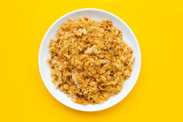 Dried shredded pork in white plate on yellow background.