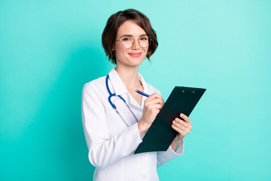 Photo portrait of nurse writing diagnosis on consultation keeping clipboard isolated bright teal color background