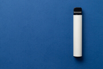 Disposable e-cigarette in white color on blue isolated background. The concept of modern smoking, vaping and nicotine. Top view