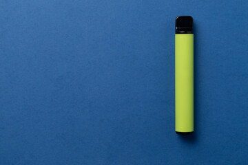 Disposable e-cigarette in green color on blue isolated background. The concept of modern smoking, vaping and nicotine. Top view