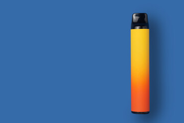 Disposable e-cigarette in yellow gradient color on blue isolated background. The concept of modern smoking, vaping and nicotine. Top view