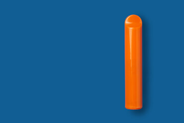 Disposable e-cigarette in orange color on blue isolated background. The concept of modern smoking, vaping and nicotine. Top view