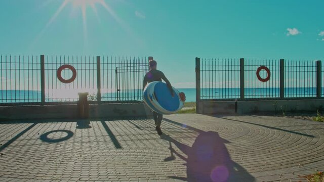 Shot of man go to water with surfboard. Male surfer on sunny day at the beach laughing and smiling, happy to be outside and do physical activity to stay healthy and fit. 4K