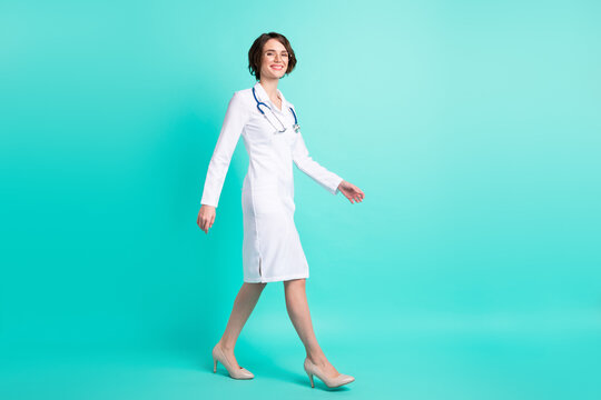 Full Length Body Size Side Profile Photo Female Doctor Walking Forward Wearing White Uniform Isolated Vivid Teal Color Background