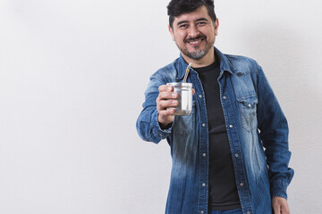 Muchacho sonriente ofreciendo un rico mate cebado con mate y bombilla de metal en fondo blanco © Guillermo