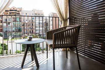 designer chair, table and ashtray on hotel balcony overlooking courtyard with everyday city life. Travel concept. Lost in quarantine, missing on excursion concept. Private area single room