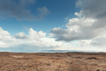 Fototapeta na wymiar Empty field and Atlantic ocean, Galway bay, Ireland. Burren mountains in the background. Nobody. Cloudy sky. Irish nature landscape. Warm sunny day.