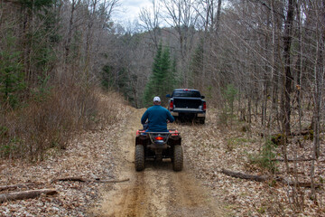 Fototapeta na wymiar Man riding ATV towards Truck in a Forest