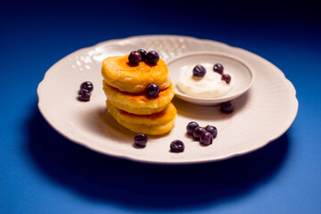 small pancakes made of cheese and flour on a white beautiful plate with a blue background delicious food