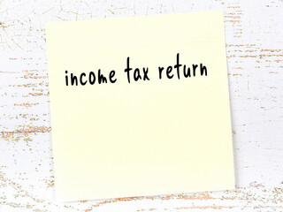 Yellow sheet of paper with word income tax return. Reminder concept