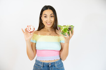 Portrait of a happy playful woman holding donuts and salad isolated over white background.