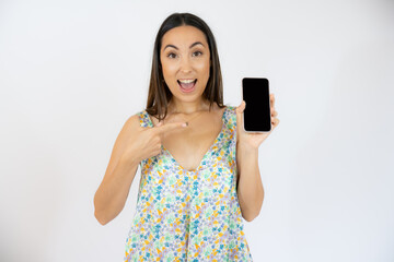 Smiling woman is showing a mobile phone standing on white background.