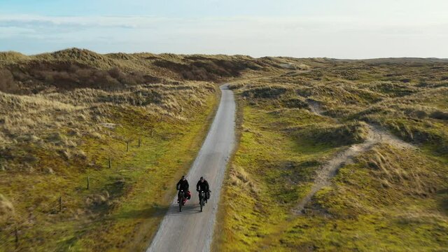 Man and woman riding bikes on dirt road, Nes, Friesland, Netherlands