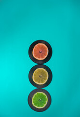 Traffic lights made of fruits and LP records. Turquoise background. Lemon, lime, grapefruit. Minimal traffic and food concept.