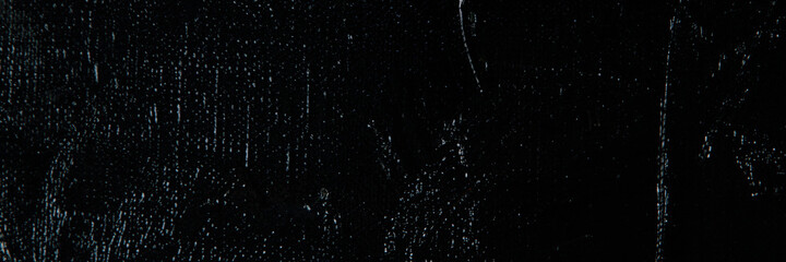Dark creative background - rough linen canvas unevenly covered with black primer, reflections of light. Toning, blurring, selective focus.