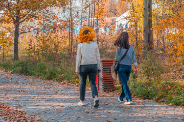 Two unrecognizable young women walking in the park