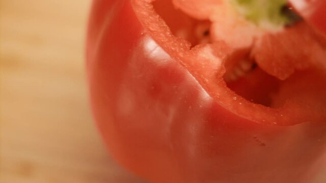 Macro shot of knife cutting red bell pepper in slow motion