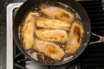 Pan-frying or home cooking fish fillet on a stove top.