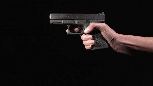 This video shows anonymous hands holding a gun against a black background and removing the clip magazine from the weapon.