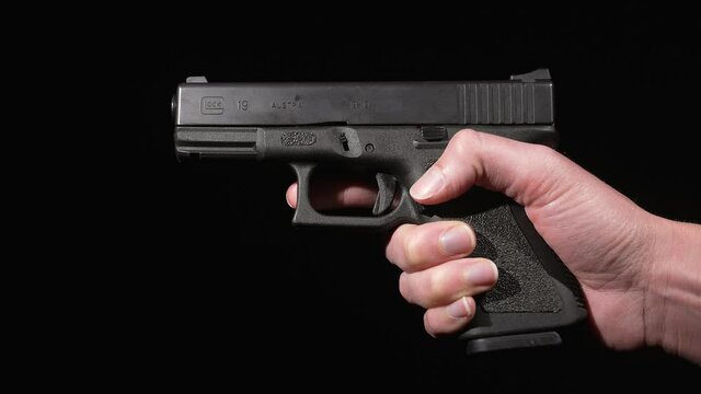 This video shows a side view of anonymous hands pulling the trigger on a 9mm gun against a black background.