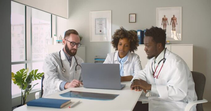 Diverse medical team meeting at hospital sitting at table and discussing patient diagnosis