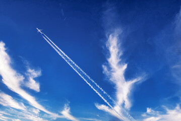 Fototapeta na wymiar 快晴の空に、飛行機が飛行機雲を描きながら飛んでいる