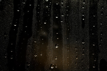 Water droplets and raindrops on clear glass at night