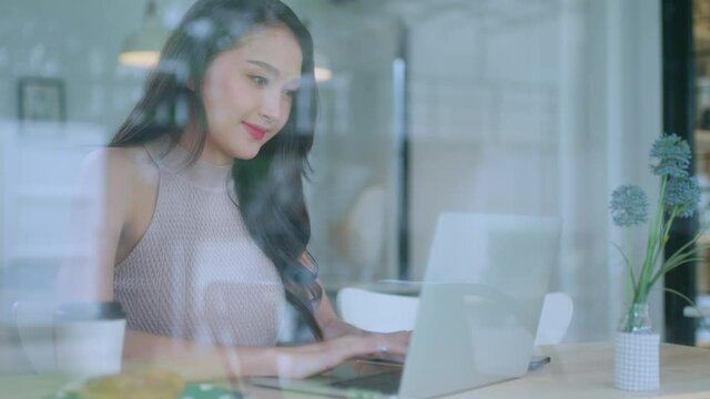 young attractive asian female wear casual cloth hand use smartphone and laptop device comminication social contact in cafe restaruant sit at counter next to big window daylight