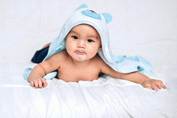 Baby boy wearing diaper with towel on white bed in bedroom