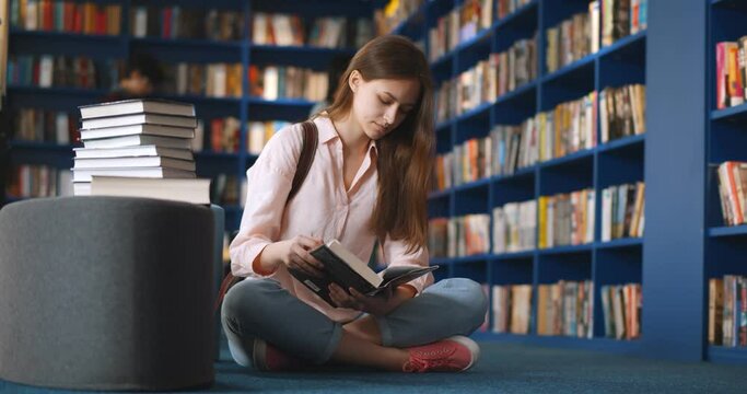 Beautiful student sitting in library and reading book
