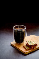 Espresso or black coffee served with creacker on wooden table and dark background. Energy drink in the morning concept.