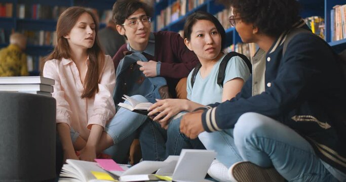 Multiracial group of students studying on library floor