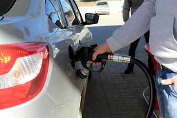 A man at a gas station refueling a car with gasoline