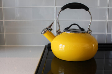 Yellow steel kettle on the gas hob on the wooden table. Modern yellow teapot on the stainless steel gas hob - Powered by Adobe