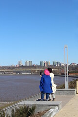 Two women stand on the banks of the river and take pictures of themselves