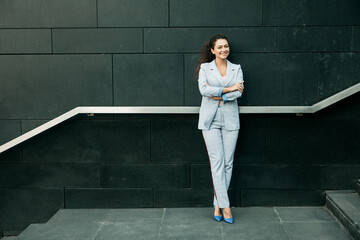 Business, people and lifestyle concept: young african woman in a stylish blue suit stands near the stairs.