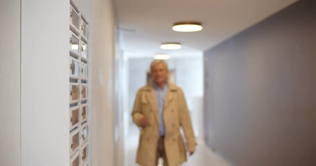 Senior man receiving refusal letter while checking mailbox in lobby