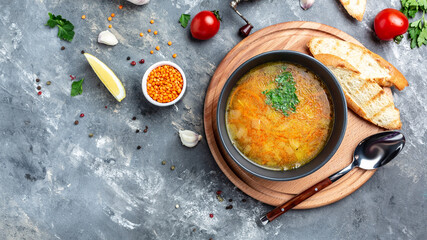 Traditional Indian soup lentils in bowl, spices, herbs on grey background. Authentic Indian dish. Top view. Long banner format, top view