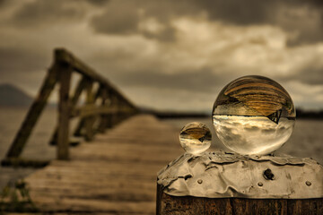Arty abstract view of the Old wooden Tokaanu wharf, lake Taupo in moody cloudy rainy weather featuring two crystal balls