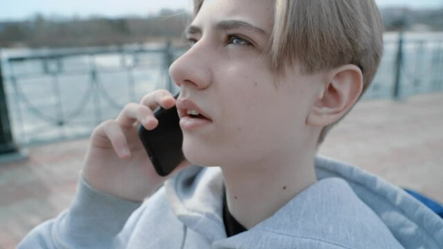 Close-up face of a teenager talking on the phone. 4K video of a teenager talking on a mobile phone in the street
