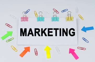 On the table there are paper clips and directional arrows, a sign that says - Marketing