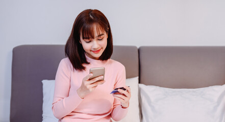 Asian woman online shopping at home. New normal daily lifestyle and Social Distancing.