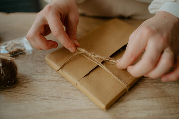 Woman tying a knot to wrap a book as birthday gift - rustic theme