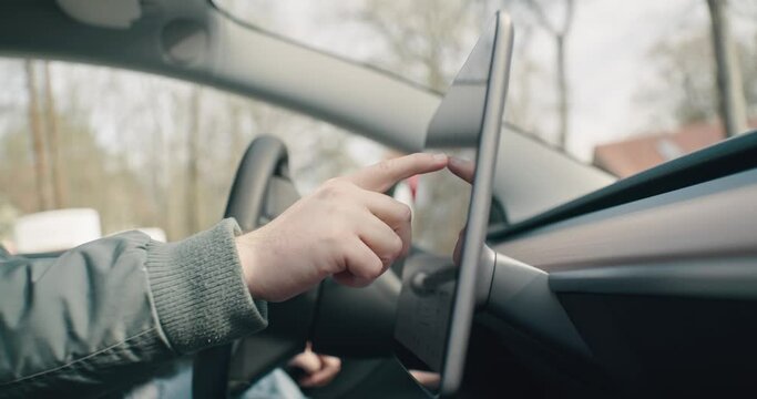 Man typing on a touchscreen in an electric car