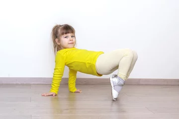 Foto op Plexiglas little girl in casual yellow clothes doing gymnastics at home © Елена Гурова