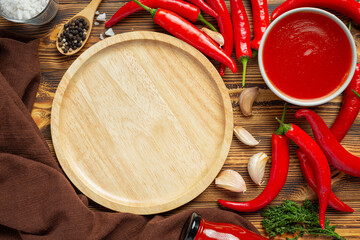 Chili sauce and peppers on dark wooden backgroud
