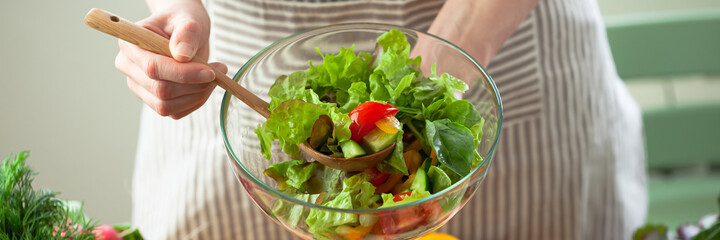 Beautiful young woman preparing delicious fresh vitamin salad. Concept of clean eating, healthy food, low calories meal, dieting, self caring lifestyle. Colorful vegetables, glass bowl. Banner