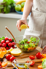 Beautiful young woman preparing delicious fresh vitamin salad with lemon dressing. Concept of clean eating, healthy food, low calories meal, dieting, self caring lifestyle. Colorful vegetables