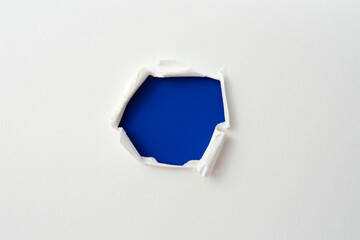 torn paper with the curled ripped sides. a round blue hole of torn on the white paper. realistic...